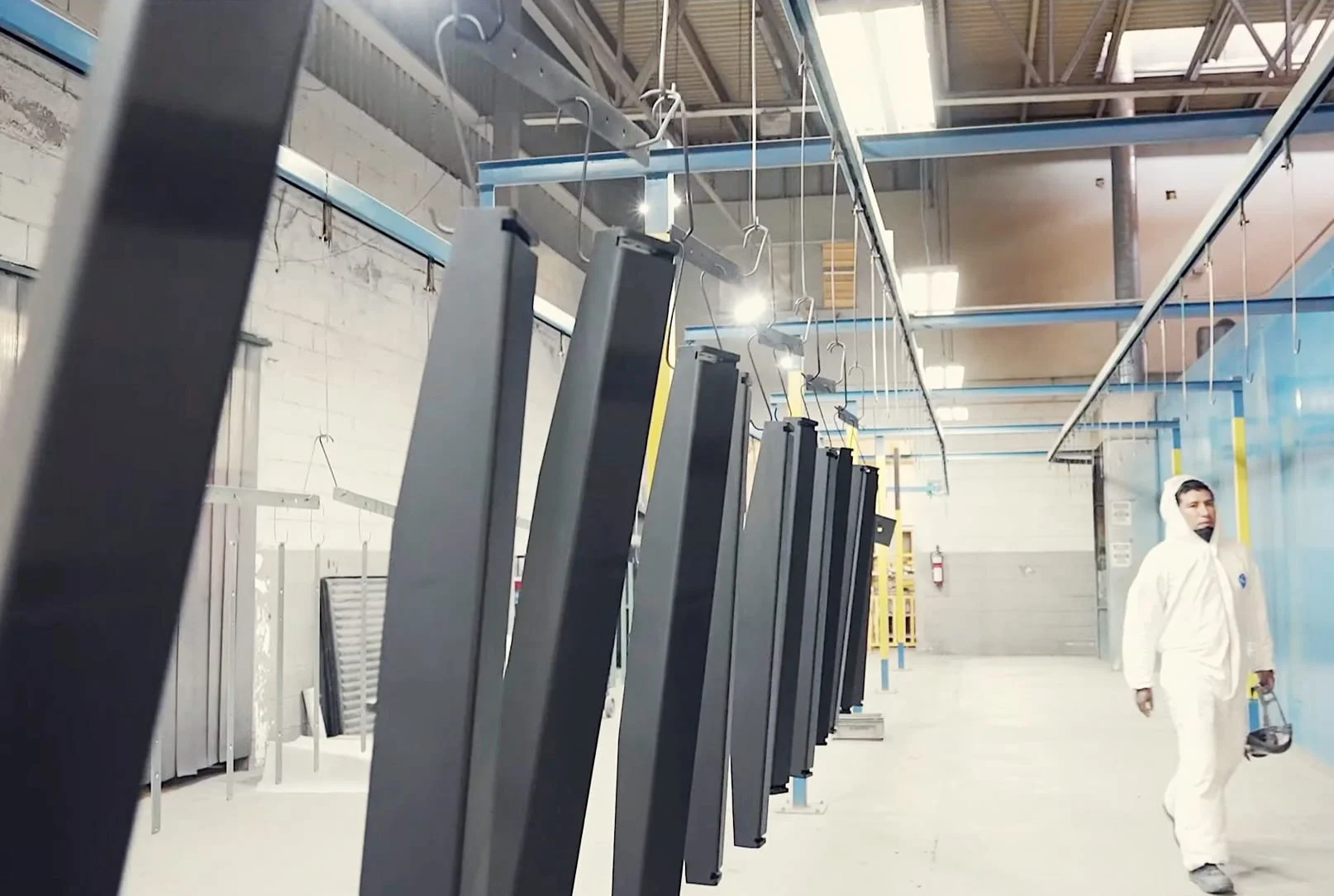 Freshly powder-coated metal parts hanging on an overhead line at Trans-Continental Manufacturing